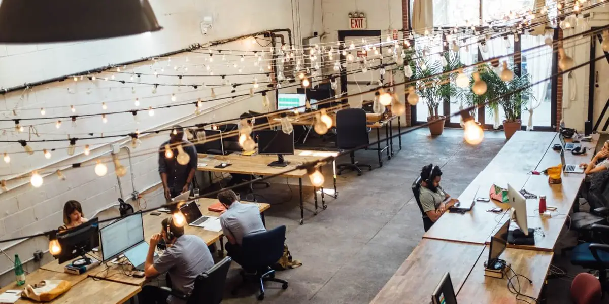 A big office space with wooden desks and a lot of lightbulbs. I'm glad I don't have to pay their energy bill.